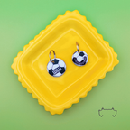 Zwei runde personalisierte Acryl-Hundemarken im Fußball-Design mit Name und Telefonnummer, auf einem gelben Tablett vor hellgrünem Hintergrund.