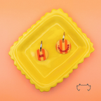 Zwei runde personalisierte Acryl-Hundemarken mit orange-gelbem Streifenmuster auf einem gelben Tablett vor orangefarbenem Hintergrund, mit Name und Telefonnummer.
