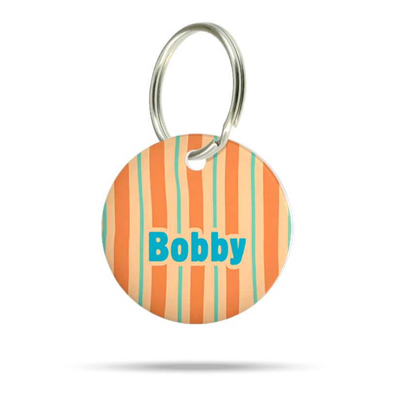 Personalisierte runde Acryl-Hundemarke für Hunde mit orangefarbenem, cremefarbenem und türkisfarbenem Streifenmuster, türkisblauem Namen „Bobby“ und silbernem Schlüsselring auf weißem Hintergrund.
