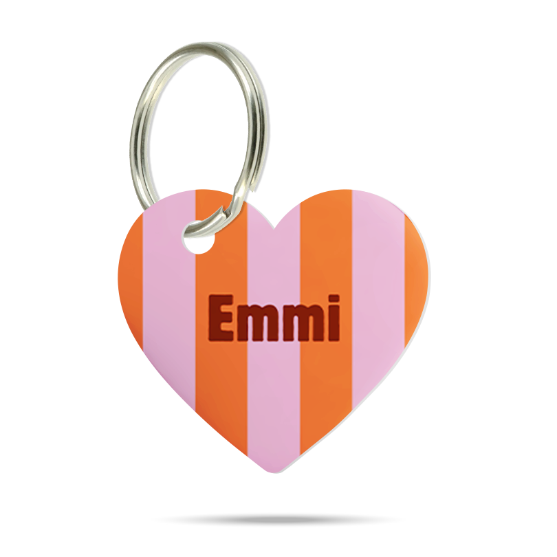 Formgeschnittene Acryl-Hundemarke in Herzform mit rosa, orange und pinkem Streifenmuster, personalisiert mit dem Namen „Emmi“ und silbernem Schlüsselring auf weißem Hintergrund.
