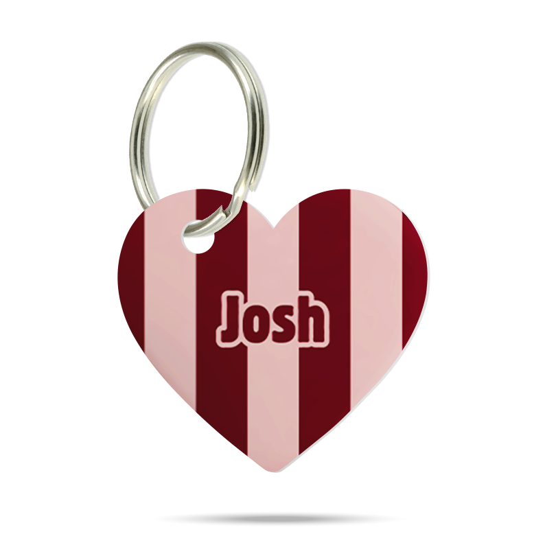 Formgeschnittene Acryl-Hundemarke in Herzform mit bordeauxrotem und rosafarbenem Streifenmuster, personalisiert mit dem Namen „Josh“ und silbernem Schlüsselring auf weißem Hintergrund.