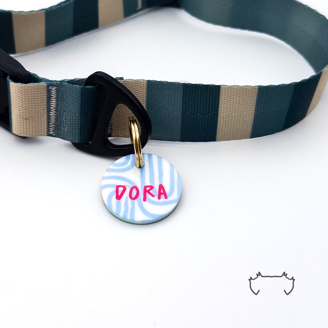 Runde personalisierte Acryl-Hundemarke mit hellblauem Blue-Maze-Muster und pinkem Namen, befestigt an einem dunkelgrün-beige gestreiften Hundehalsband.