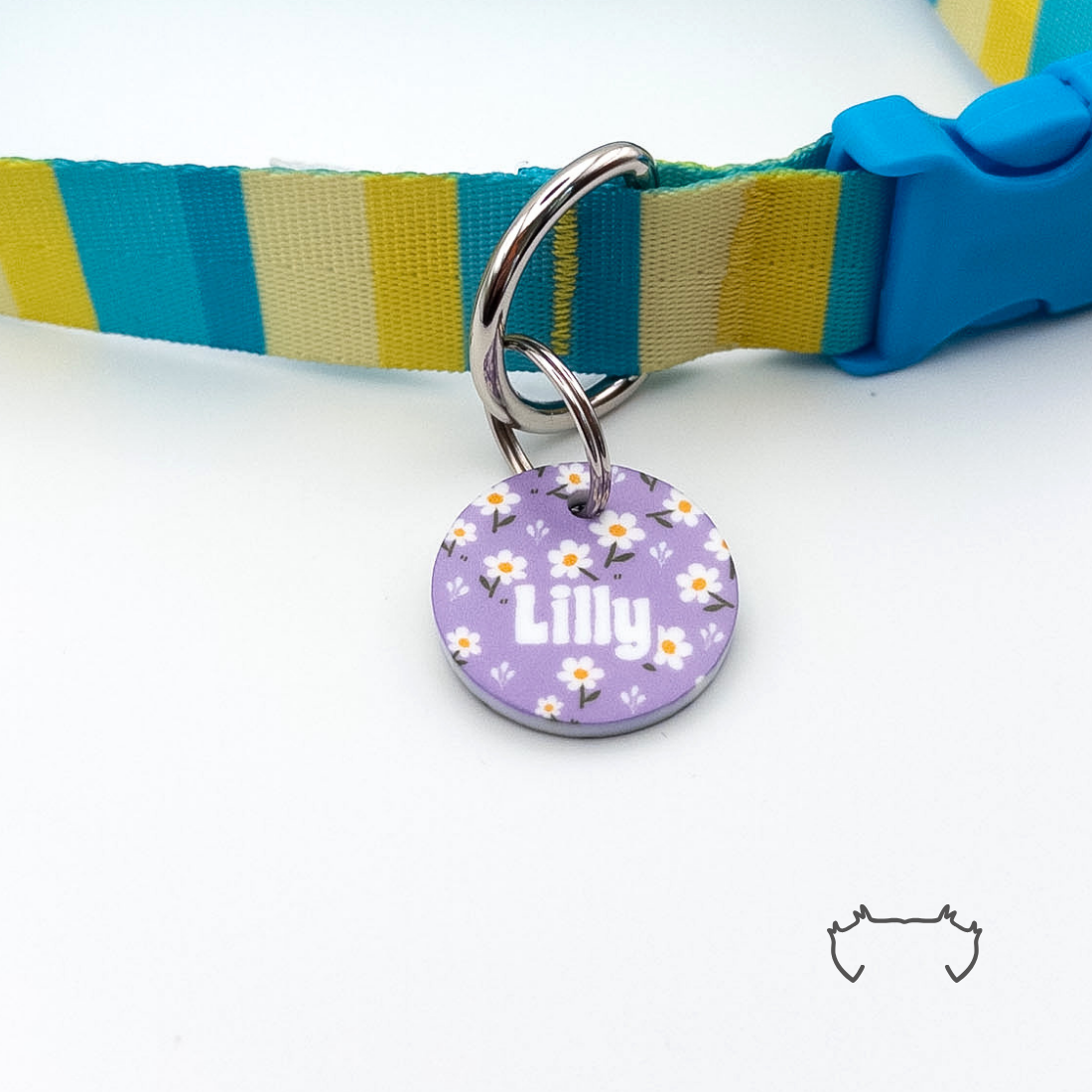 Personalisierte runde Acryl-Hundemarke mit lila Gänseblümchen-Muster und Name „Lilly“, befestigt an einem türkis-gelb-beige gestreiften Hundehalsband mit blauem Verschluss.