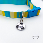 Runde personalisierte Acryl-Hundemarke im schwarz-weißen Fußball-Design, befestigt an einem türkis-gelb gestreiften Hundehalsband mit blauem Verschluss.