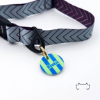 Personalisierte runde Acryl-Hundemarke mit neonfarbenem Streifenmuster in Grün und Blau, befestigt an einem dunklen Hundehalsband mit grafischem Chevron-Muster.