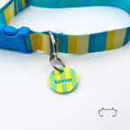 Runde personalisierte Acryl-Hundemarke mit neon-gelbem und grünem Streifenmuster, befestigt an einem türkis-gelb gestreiften Hundehalsband mit blauem Verschluss.