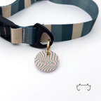 Personalisierte runde Hundemarke aus Acryl mit grün-rosa Wellenmuster, befestigt an einem dunkelgrün-beige gestreiften Hundehalsband mit schwarzem Verschluss.