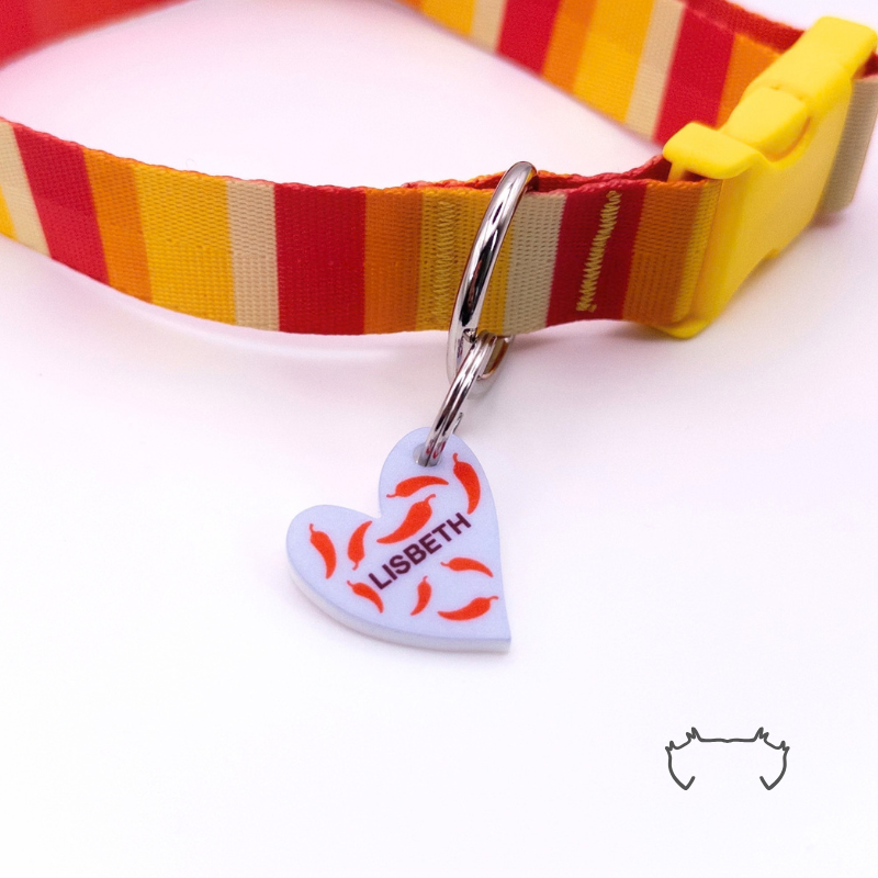 Bunte personalisierte Acryl-Hundemarke in Herzform mit roten Chili-Motiven und Name „LISBETH“, befestigt an einem rot-gelb gestreiften Hundehalsband mit gelbem Verschluss.
