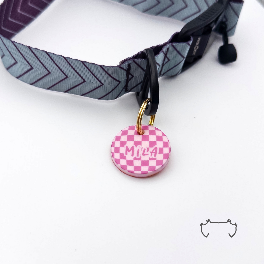 Runde personalisierte Acryl-Hundemarke mit pinkem Karomuster, befestigt an einem grauen Hundehalsband mit dunklem Chevron-Muster.