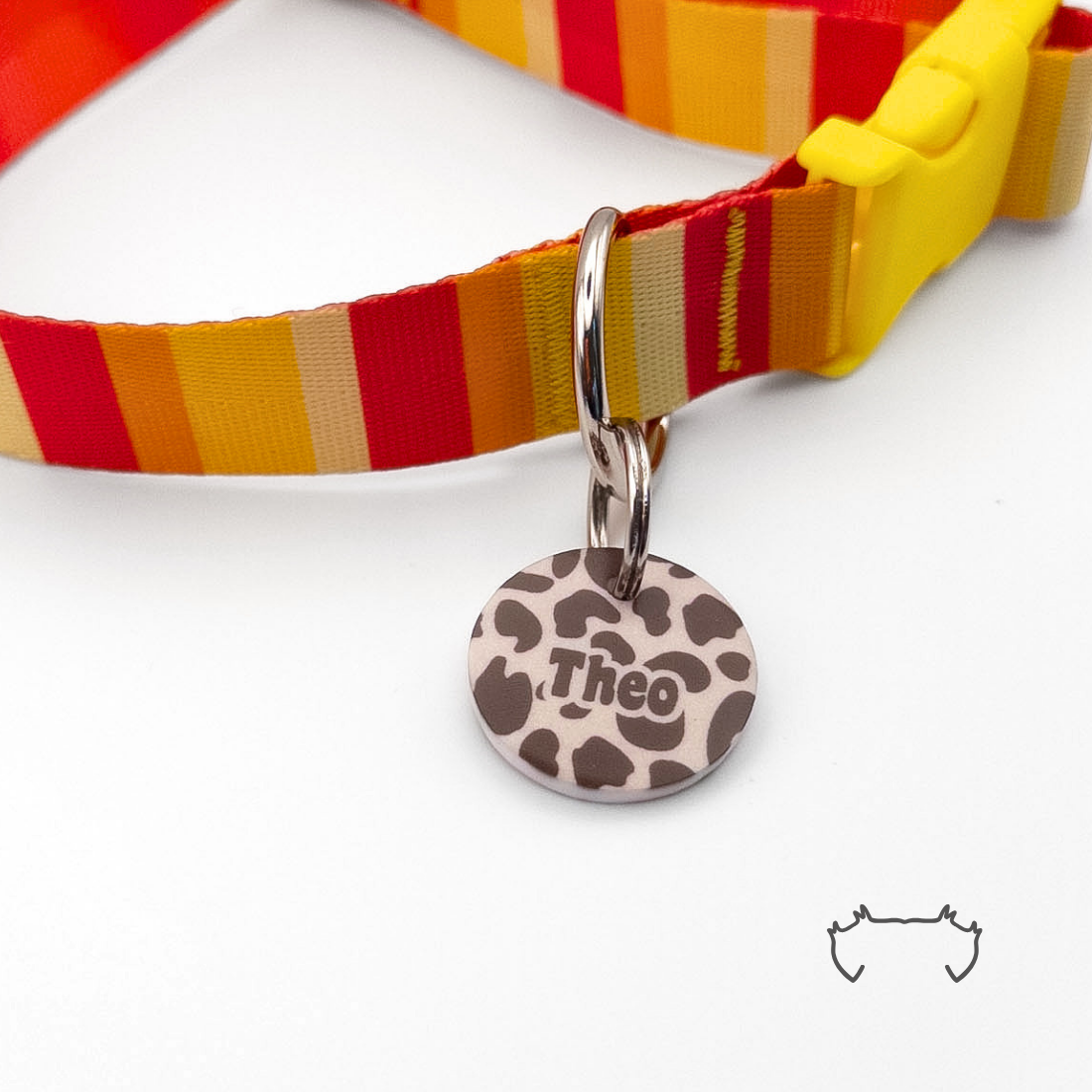 Runde personalisierte Acryl-Hundemarke im beige-braunen Leopard-Design, befestigt an einem rot-gelb gestreiften Hundehalsband mit gelbem Verschluss.