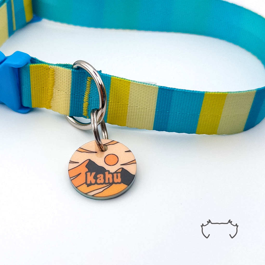 Personalisierte runde Acryl-Hundemarke mit orange-beigem Bergdesign und Sonne, befestigt an einem türkis-gelb-beige gestreiften Hundehalsband.