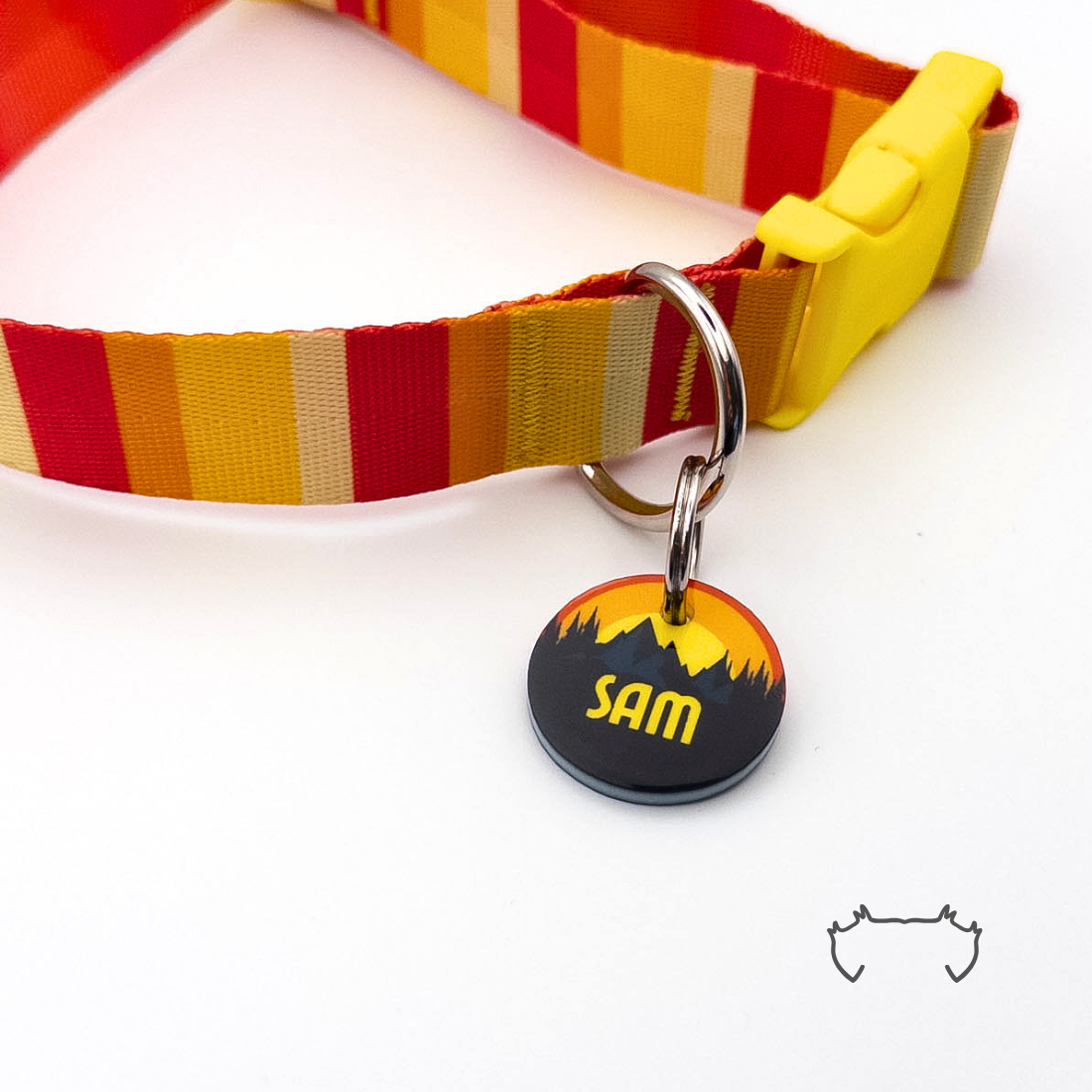 Runde personalisierte Hundemarke aus Acryl mit dunklem Sonnenuntergangs- und Bergmotiv, befestigt an einem rot-gelb gestreiften Hundehalsband mit gelbem Verschluss.