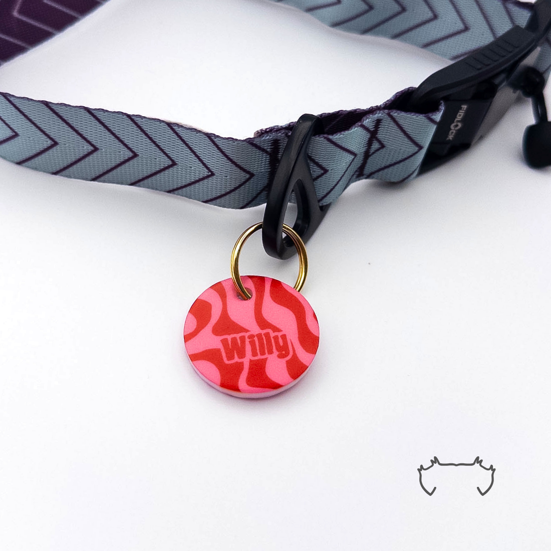 Runde Acryl-Hundemarke mit rotem und pinkem Wellenmuster, befestigt an einem grauen Hundehalsband mit dunklem Chevron-Muster und schwarzem Verschluss.