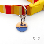 Runde personalisierte Acryl-Hundemarke mit Segelboot- und Meer-Design in Blau und Beige, befestigt an einem rot-gelb gestreiften Hundehalsband mit gelbem Verschluss.