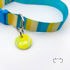 Runde personalisierte Acryl-Hundemarke im gelben Tennisball-Design, befestigt an einem türkis-gelb gestreiften Hundehalsband mit blauem Verschluss.