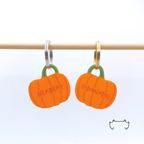 Zwei formgeschnittene, leichte Acryl-Hundemarken in Kürbisform an einer hellen Holzstange, mit orangefarbenem Design, Name und Telefonnummer. Bunte personalisierte Hundemarke für Hunde im herbstlichen Kürbis-Look.