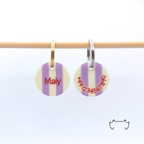 Vorder- und Rückseite einer runden Acryl-Hundemarke mit pastellgelben und lila Streifen, Name und Telefonnummer an einer Holzstange.
