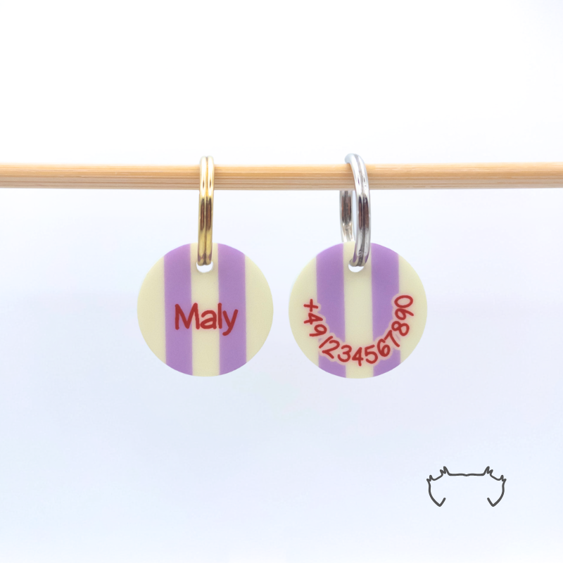 Vorder- und Rückseite einer runden Acryl-Hundemarke mit pastellgelben und lila Streifen, Name und Telefonnummer an einer Holzstange.