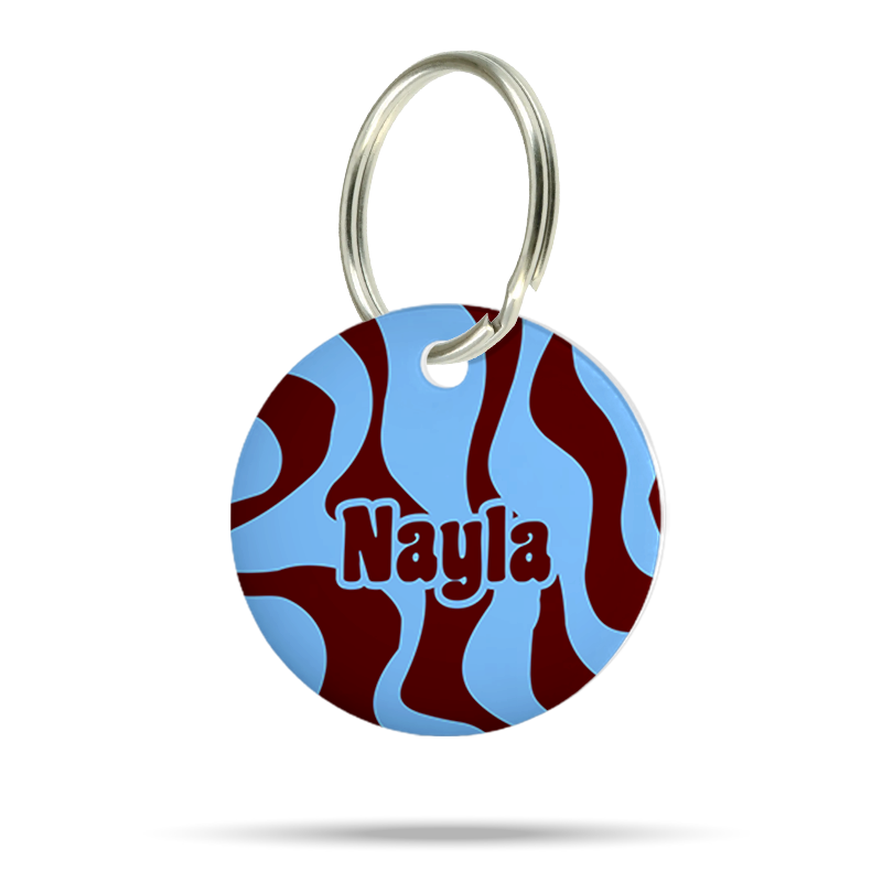 Personalisierte runde Hundemarke aus Acryl mit blauem und bordeauxrotem Wellenmuster, Name „Nayla“ und silbernem Schlüsselring auf weißem Hintergrund.