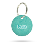 Personalisierte runde Hundemarke aus Acryl im türkisfarbenen Croco-Muster mit Name „Paula“ und silbernem Schlüsselring auf weißem Hintergrund.