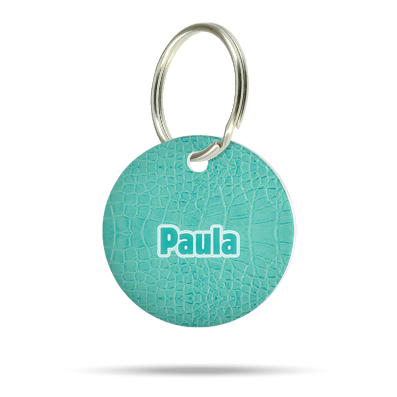 Personalisierte runde Hundemarke aus Acryl im türkisfarbenen Croco-Muster mit Name „Paula“ und silbernem Schlüsselring auf weißem Hintergrund.