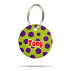 Personalisierte runde Hundemarke aus Acryl mit grünem Hintergrund, lila Punkten, rotem Namen „Tony“ und silbernem Schlüsselring auf weißem Hintergrund.