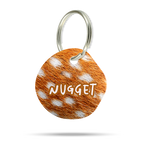 Personalisierte Acryl-Hundemarke in organischer Blob-Form mit braun-weißem Reh Animal Print, Name Nugget und Metallring.