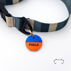 Personalisierte runde Acryl-Hundemarke mit kräftigem Streifen- oder Colorblock-Design in Orange und Blau, befestigt an einem dunkelgrün-beige gestreiften Hundehalsband.