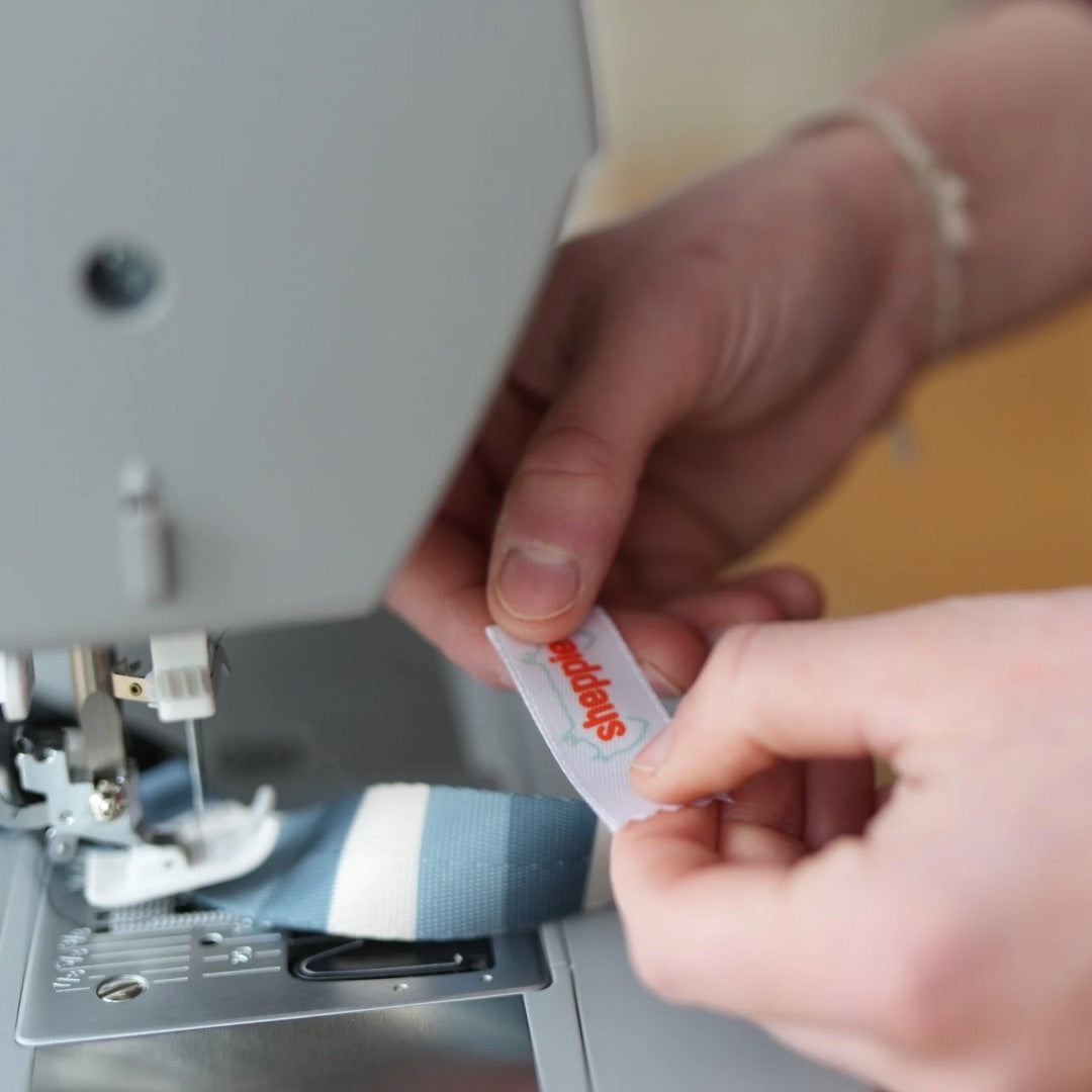 Aileen von Sheppie Manufaktur sitzt an ihrer Nähmaschine und näht ein Halsband. 